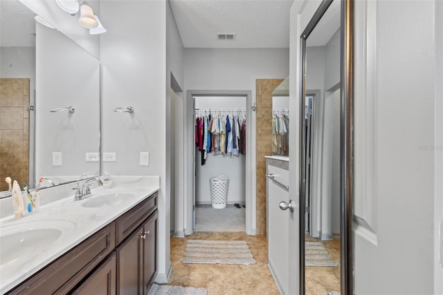 123 N Starling Dr, Palm Coast, FL 32164 - full bathroom with a spacious closet, double vanity, a textured ceiling, and tile patterned flooring