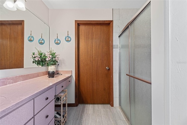 full bath featuring a shower stall, wood finished floors, and vanity