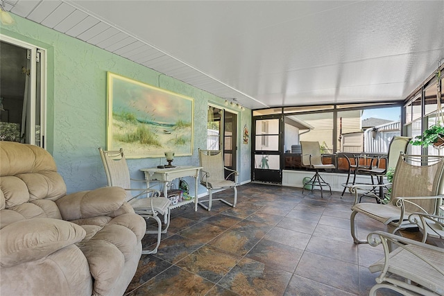 sunroom / solarium with a textured wall and stone finish flooring