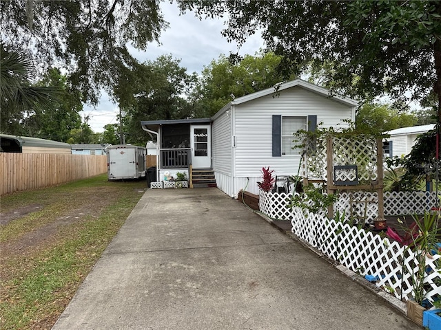 manufactured / mobile home featuring a sunroom, fence, and concrete driveway