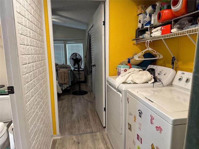 laundry area with washing machine and dryer and light wood-type flooring