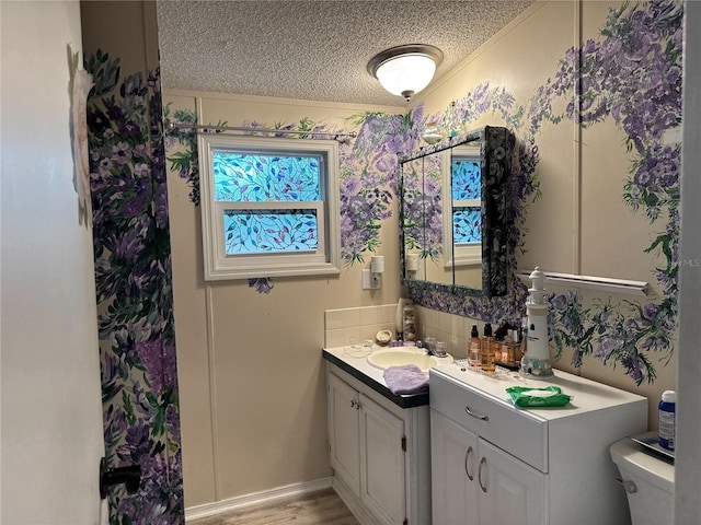 bathroom featuring a textured ceiling, vanity, toilet, crown molding, and wood finished floors
