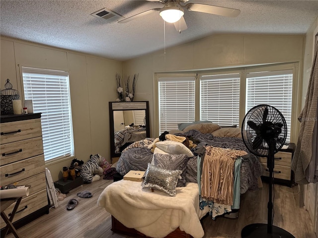 bedroom with lofted ceiling, wood finished floors, a textured ceiling, and ceiling fan