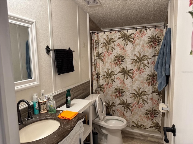 full bath with a textured ceiling, vanity, curtained shower, wood finished floors, and toilet