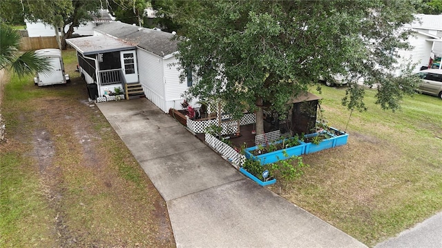 view of front facade featuring driveway, fence, and a sunroom