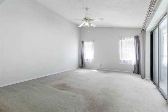 unfurnished room with lofted ceiling, plenty of natural light, a textured ceiling, light colored carpet, and ceiling fan