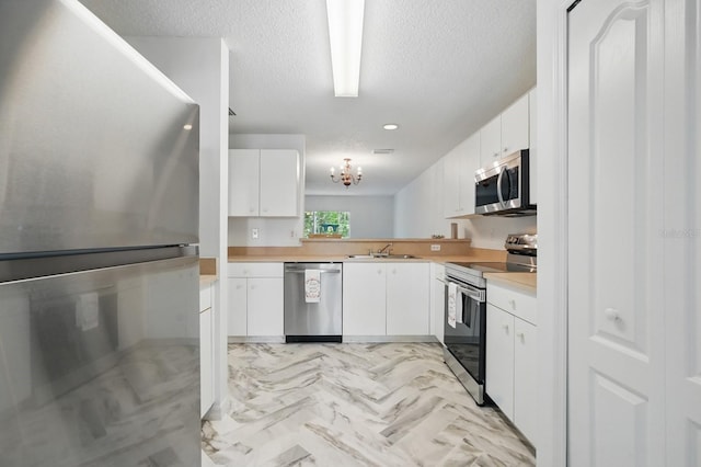 1502 Deer Springs Rd, Port Orange, FL 32129 - kitchen featuring stainless steel appliances, a sink, light countertops, white cabinetry, and a textured ceiling