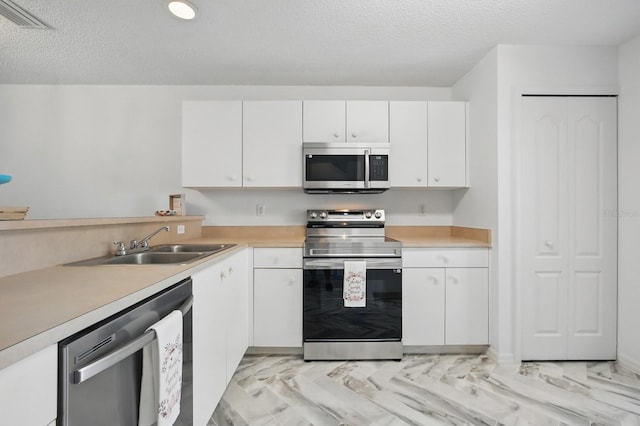 1502 Deer Springs Rd, Port Orange, FL 32129 - kitchen featuring appliances with stainless steel finishes, a sink, light countertops, white cabinets, and a textured ceiling
