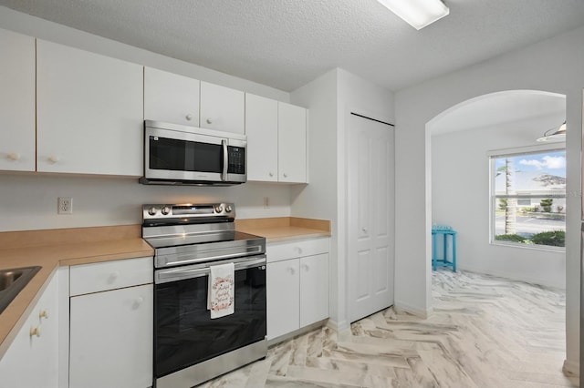 1502 Deer Springs Rd, Port Orange, FL 32129 - kitchen with stainless steel appliances, light countertops, arched walkways, white cabinets, and a textured ceiling