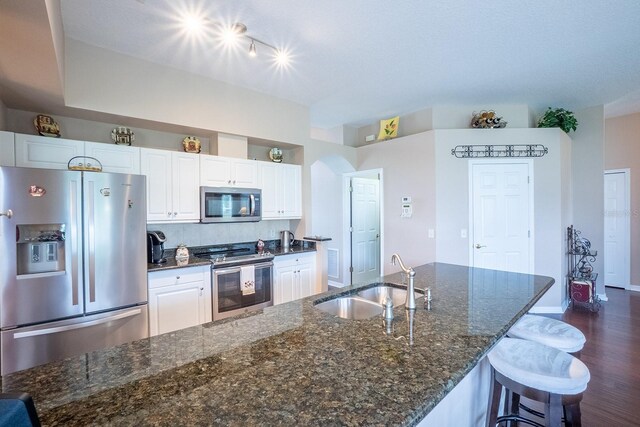 30 Westridge Ln, Palm Coast, FL 32164 - kitchen with stainless steel appliances, a sink, white cabinets, dark wood-style floors, and a kitchen breakfast bar