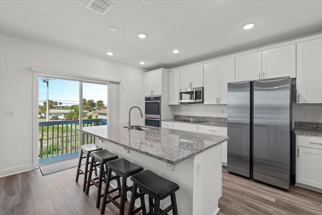 3828 S Atlantic Ave, Daytona Beach, FL 32118 - kitchen with appliances with stainless steel finishes, a center island with sink, wood finished floors, white cabinetry, and recessed lighting