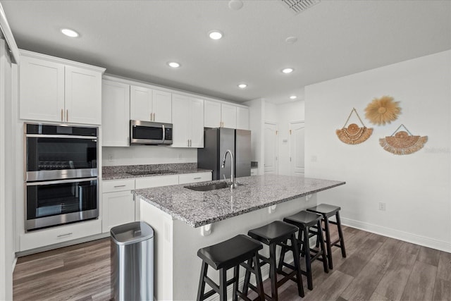 3828 S Atlantic Ave, Daytona Beach, FL 32118 - kitchen with appliances with stainless steel finishes, a center island with sink, recessed lighting, dark wood-type flooring, and light stone counters