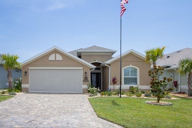 37 Lagoon Way, Palm Coast, FL 32137 - single story home with stucco siding, a front yard, an attached garage, and decorative driveway