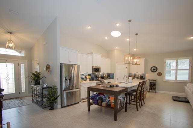 37 Lagoon Way, Palm Coast, FL 32137 - kitchen featuring appliances with stainless steel finishes, white cabinets, a sink, an island with sink, and backsplash