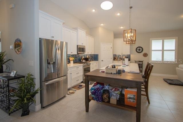 37 Lagoon Way, Palm Coast, FL 32137 - kitchen with appliances with stainless steel finishes, backsplash, white cabinets, light countertops, and a chandelier
