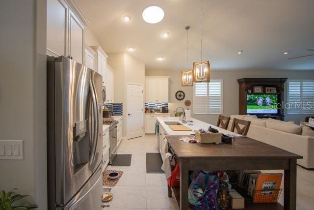 37 Lagoon Way, Palm Coast, FL 32137 - kitchen with stainless steel appliances, a sink, an island with sink, white cabinets, and open floor plan