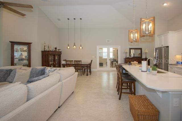 37 Lagoon Way, Palm Coast, FL 32137 - living room with high vaulted ceiling, french doors, a chandelier, and a ceiling fan