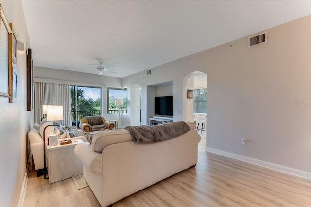 200 Riverfront Dr Unit B204, Palm Coast, FL 32137 - living room featuring arched walkways, a ceiling fan, light wood-style floors, and healthy amount of natural light