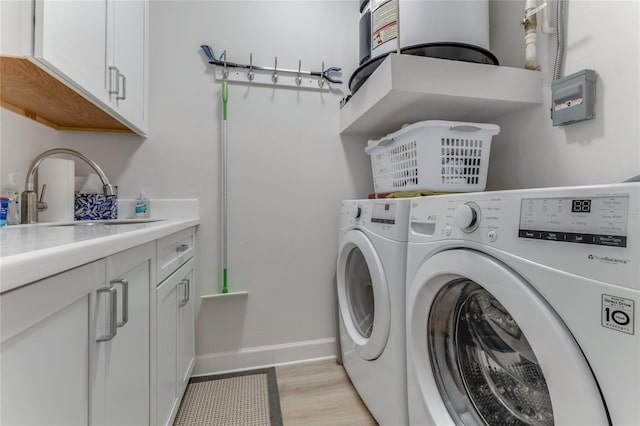 200 Riverfront Dr Unit B204, Palm Coast, FL 32137 - laundry room featuring washing machine and clothes dryer, cabinet space, baseboards, water heater, and light wood-style flooring