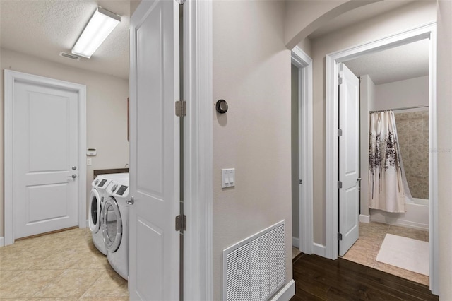 716 Woodbridge Ct, Ormond Beach, FL 32174 - clothes washing area with washing machine and clothes dryer, arched walkways, baseboards, wood finished floors, and a textured ceiling