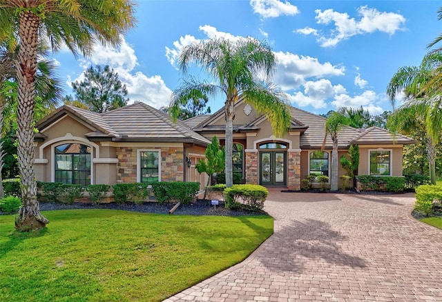 716 Woodbridge Ct, Ormond Beach, FL 32174 - view of front facade with french doors, stucco siding, decorative driveway, a front yard, and stone siding