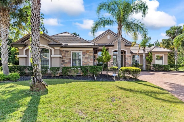 716 Woodbridge Ct, Ormond Beach, FL 32174 - view of front facade featuring stucco siding, a front lawn, stone siding, and a tile roof