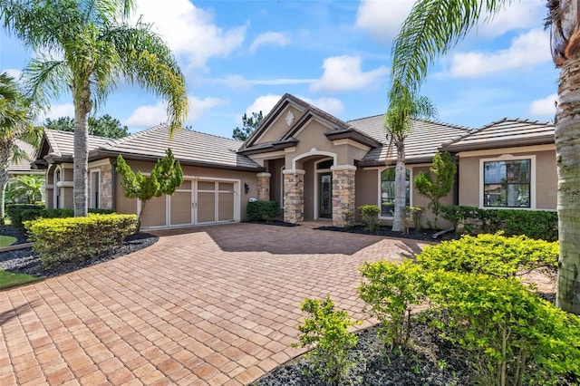 716 Woodbridge Ct, Ormond Beach, FL 32174 - view of front of house with stucco siding, decorative driveway, a garage, stone siding, and a tiled roof