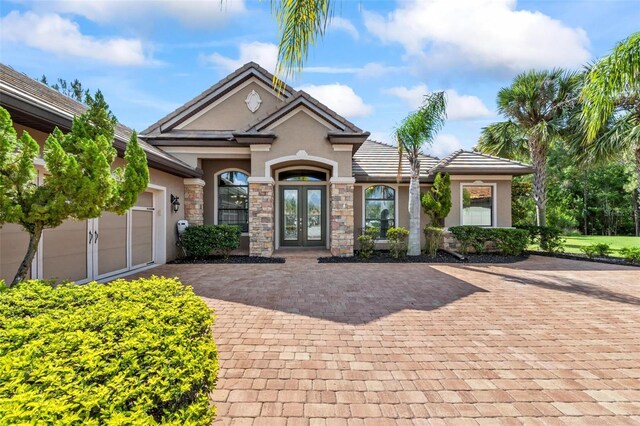716 Woodbridge Ct, Ormond Beach, FL 32174 - view of front of house featuring french doors, stucco siding, driveway, stone siding, and an attached garage