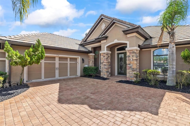 716 Woodbridge Ct, Ormond Beach, FL 32174 - view of front of house with stucco siding, a tiled roof, a garage, stone siding, and decorative driveway