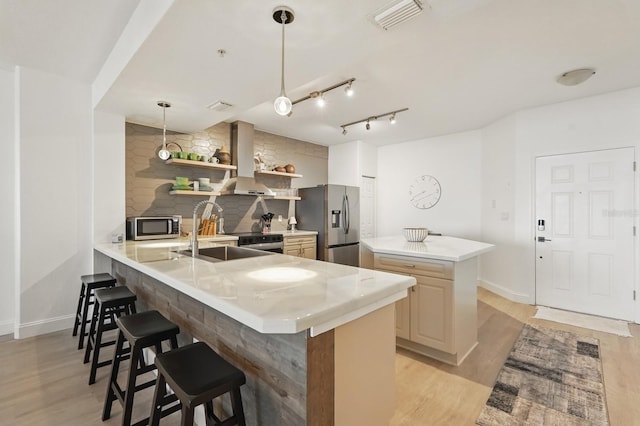 80 Surfview Dr Unit 511, Palm Coast, FL 32137 - kitchen featuring appliances with stainless steel finishes, a sink, wall chimney range hood, a kitchen bar, and light wood-style flooring