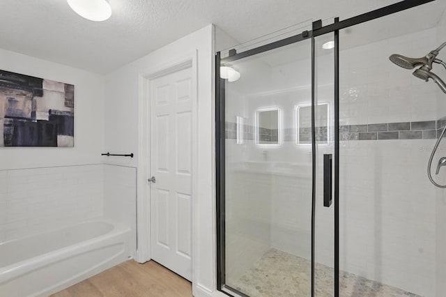 80 Surfview Dr Unit 511, Palm Coast, FL 32137 - full bathroom with a bath, a shower stall, wood finished floors, and a textured ceiling