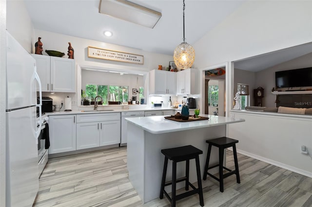 135 Lambert Ave, Flagler Beach, FL 32136 - kitchen with white appliances, light countertops, a sink, a breakfast bar area, and white cabinetry