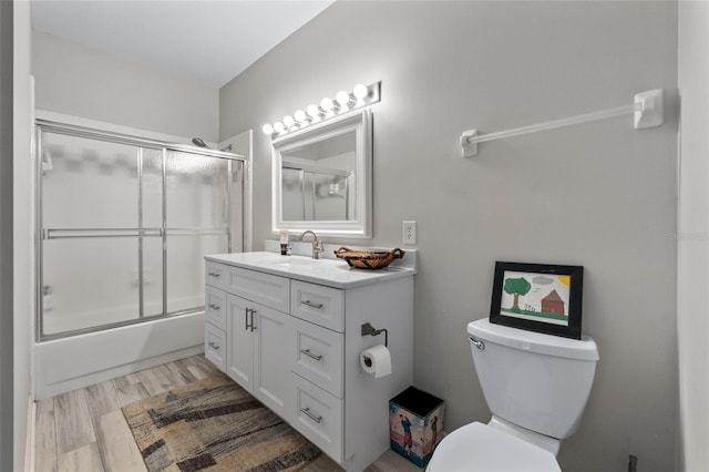 135 Lambert Ave, Flagler Beach, FL 32136 - bathroom with toilet, vanity, bath / shower combo with glass door, and wood finished floors
