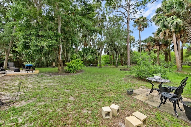 135 Lambert Ave, Flagler Beach, FL 32136 - view of grassy yard featuring an outdoor fire pit, a patio, and view of wooded area