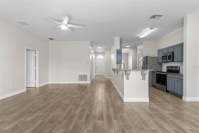 kitchen featuring stainless steel appliances, a breakfast bar, a peninsula, and light wood-style floors