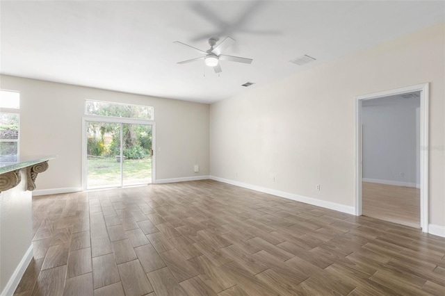 unfurnished living room with wood finished floors, ceiling fan, plenty of natural light, and baseboards