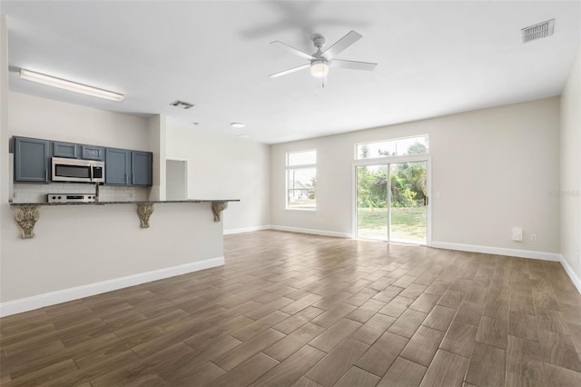 unfurnished living room with dark wood-style flooring, a ceiling fan, and baseboards