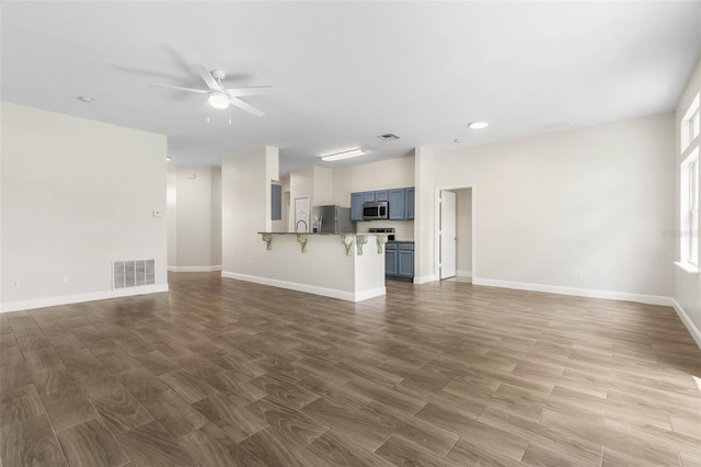 unfurnished living room with a ceiling fan, baseboards, wood finished floors, and recessed lighting