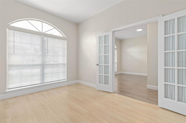 empty room with wood finished floors, french doors, and baseboards