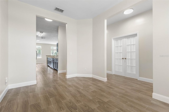 unfurnished room featuring wood finished floors, baseboards, and french doors
