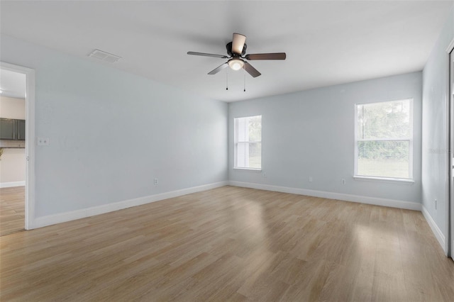 empty room with a ceiling fan, light wood finished floors, and baseboards