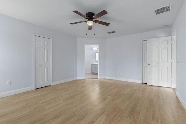 unfurnished bedroom featuring light wood finished floors, baseboards, ensuite bathroom, and ceiling fan