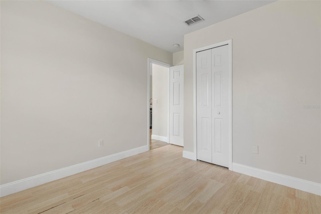 unfurnished bedroom featuring light wood-style flooring, baseboards, and a closet