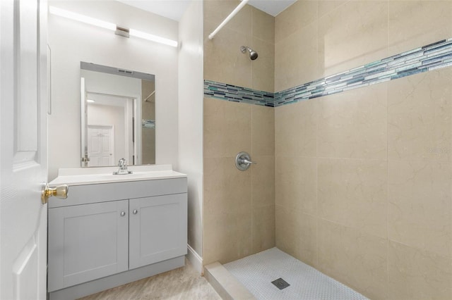 bathroom featuring tiled shower and vanity