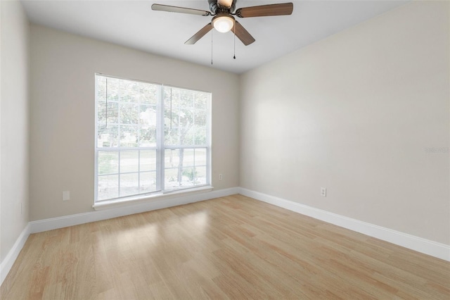 spare room with light wood-type flooring, baseboards, and a ceiling fan