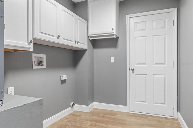 laundry area with cabinet space, baseboards, hookup for a washing machine, and light wood-type flooring
