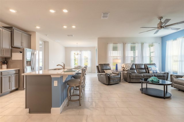 2840 Monaghan Dr, Ormond Beach, FL 32174 - kitchen featuring gray cabinetry, open floor plan, stainless steel fridge, a ceiling fan, and a kitchen bar
