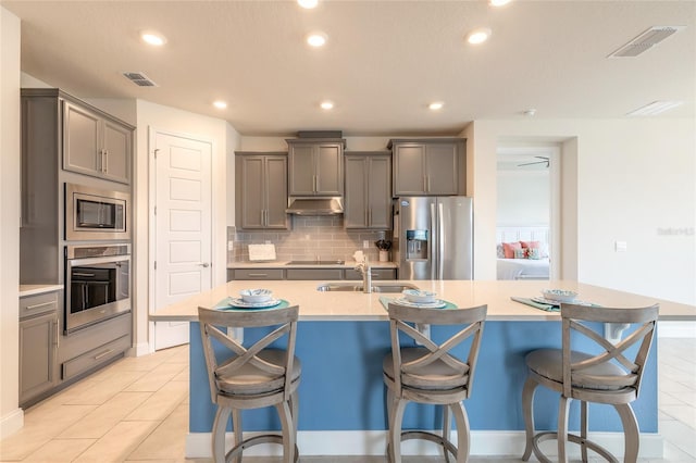 2840 Monaghan Dr, Ormond Beach, FL 32174 - kitchen featuring appliances with stainless steel finishes, gray cabinetry, under cabinet range hood, backsplash, and recessed lighting
