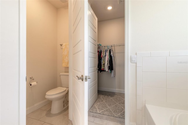 2840 Monaghan Dr, Ormond Beach, FL 32174 - bathroom with toilet, a walk in closet, tile patterned flooring, a tub to relax in, and baseboards