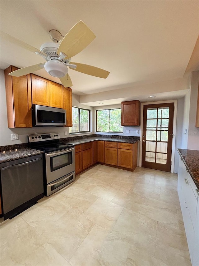 20 Blakeshire Pl, Palm Coast, FL 32137 - kitchen with appliances with stainless steel finishes, brown cabinetry, a ceiling fan, and dark stone counters